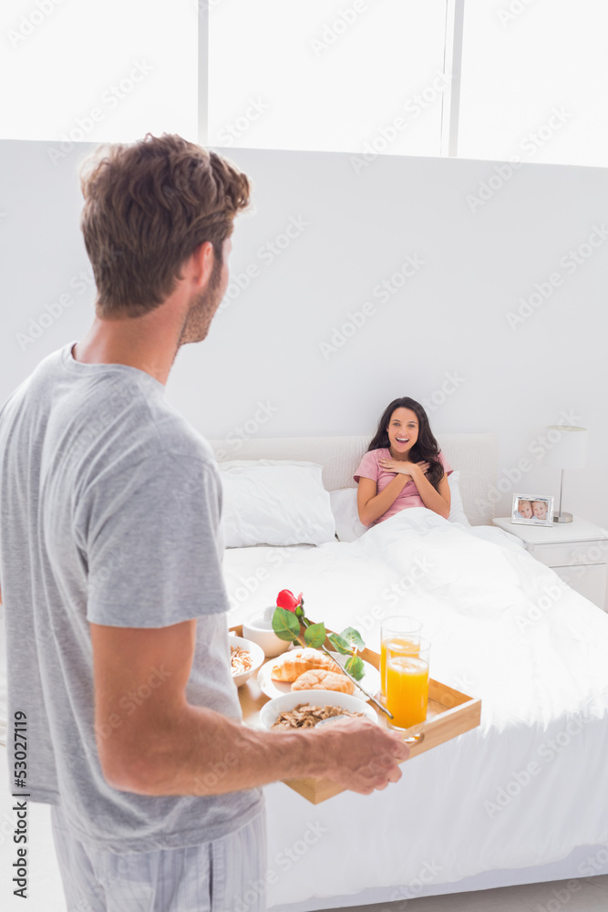 Man bringing breakfast to his surprised wife