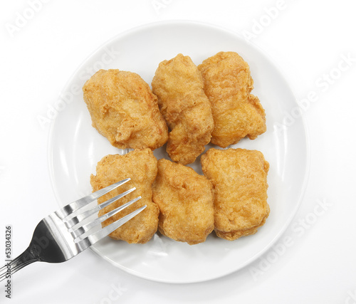 chicken nuggets with fork on white plate