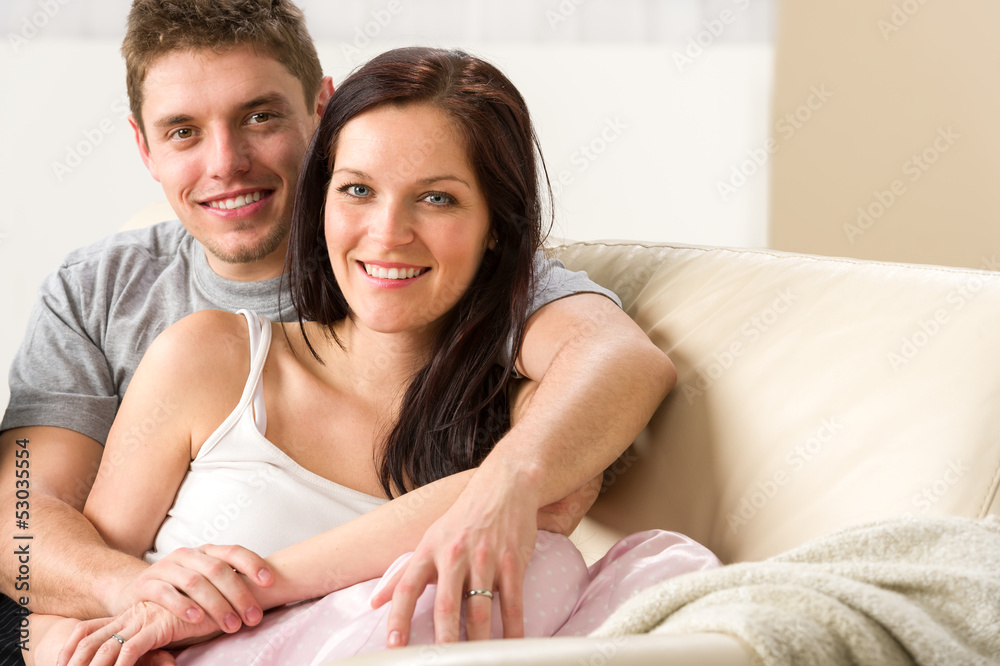 Carefree young couple embracing on couch Carefree young couple embracing on couch