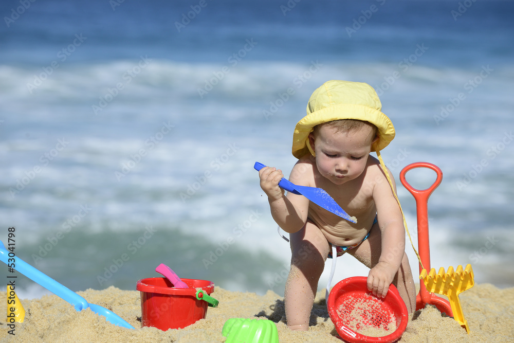 Baby playing with beach toys in the sand Baby playing with beach toys in the sand