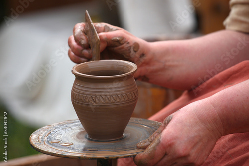 hands of a potter, creating an earthen jar on the potter's wheel