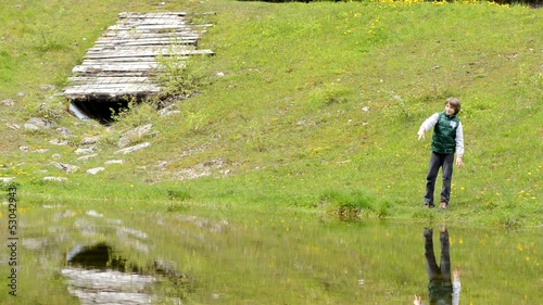 child throws a stone in the pond photo