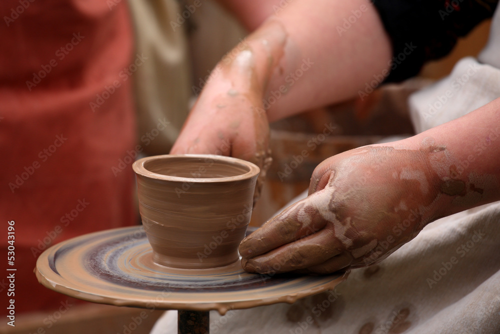 hands of a potter, creating an earthen jar on the potter's wheel