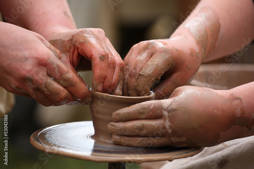 hands of a potter, creating an earthen jar on the potter's wheel