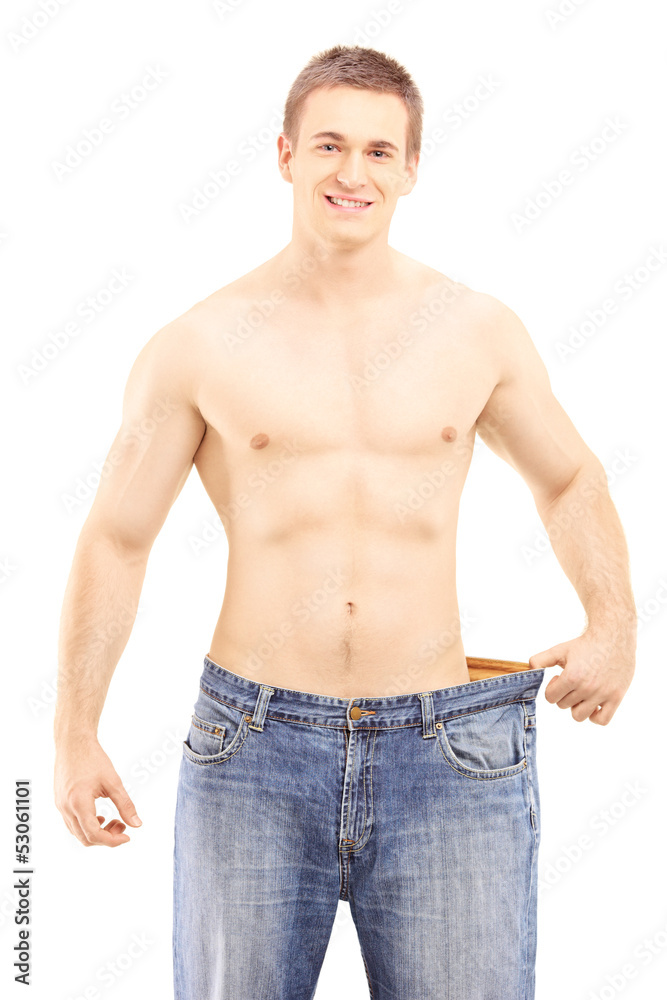 Shirtless smiling male showing his lost weight by putting on an Shirtless smiling male showing his lost weight by putting on an