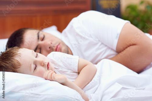 father and baby sleeping peacefully in bed