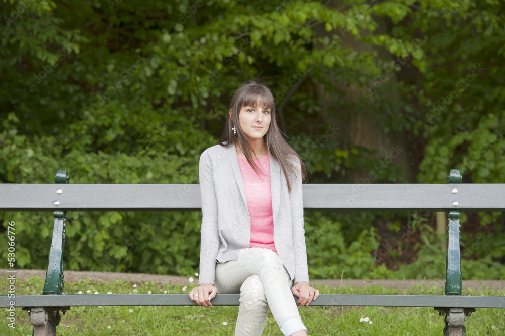 young woman seated on a bench in the park young woman seated on a bench in the park