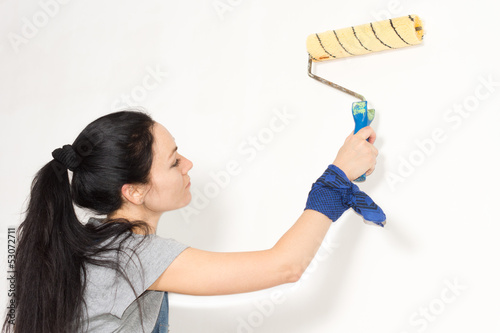 Woman painting a wall with a roller