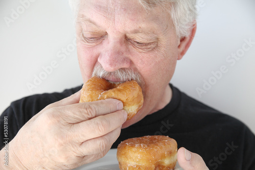 man biting into fresh doughnut