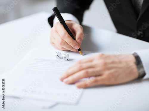 man hands with gambling dices signing contract