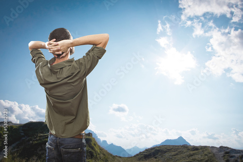 young man on top of the mountain, realxing and enjoying the view