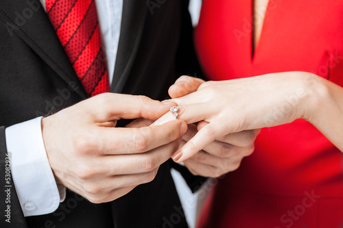 man putting wedding ring on woman hand