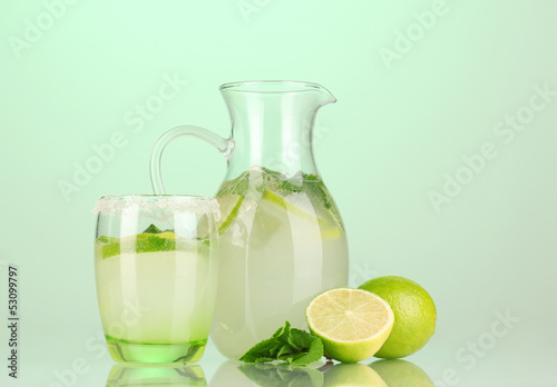 Lemonade in pitcher and glass on turquoise background