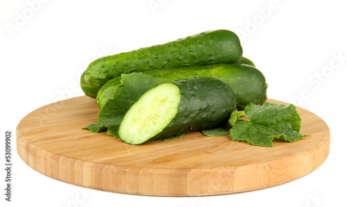Tasty green cucumbers on wooden cutting board, isolated on