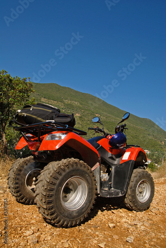 Red quad in the countryside and blue sky in the background