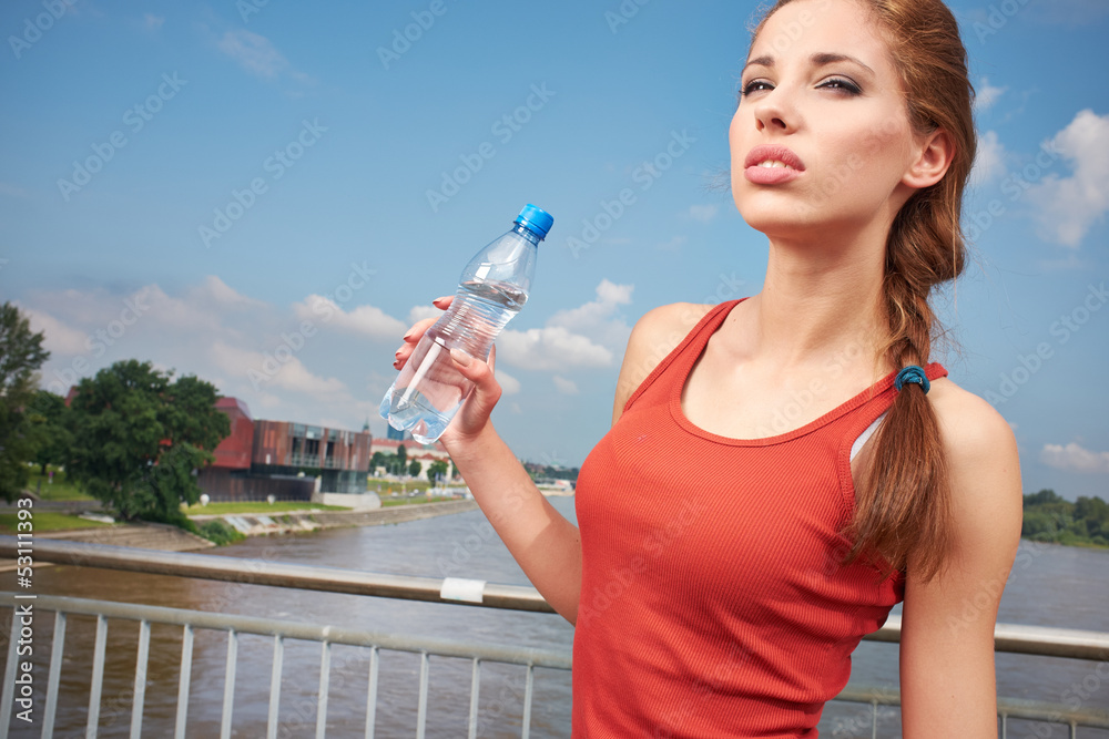Young woman drinking water at outdoors workout