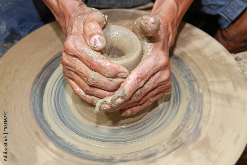 Close-up of hands making pottery on pottery wheel