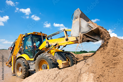 Excavator machine unloading sand during earth moving works