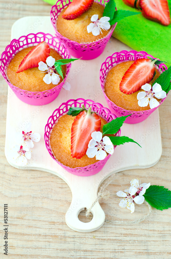 Muffins with strawberries on a wooden table