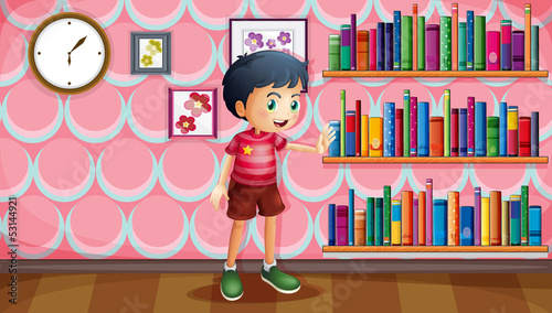 A boy standing beside the wooden shelves with books