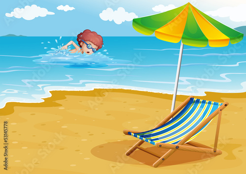 A boy swimming at the beach with a chair and an umbrella