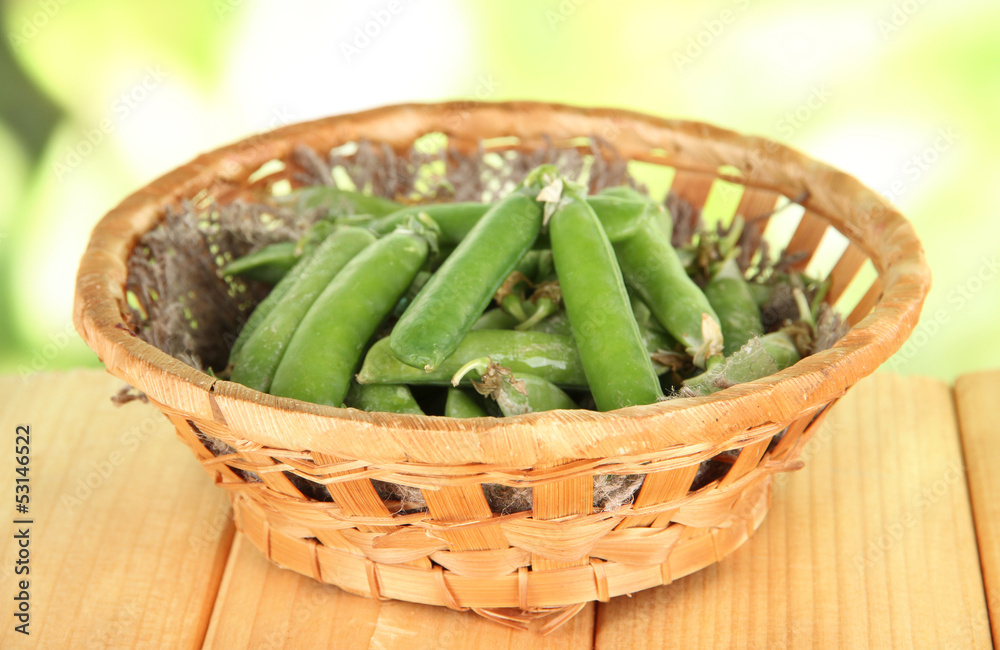 Green peas in basket on wooden table on nature background Green peas in basket on wooden table on nature background