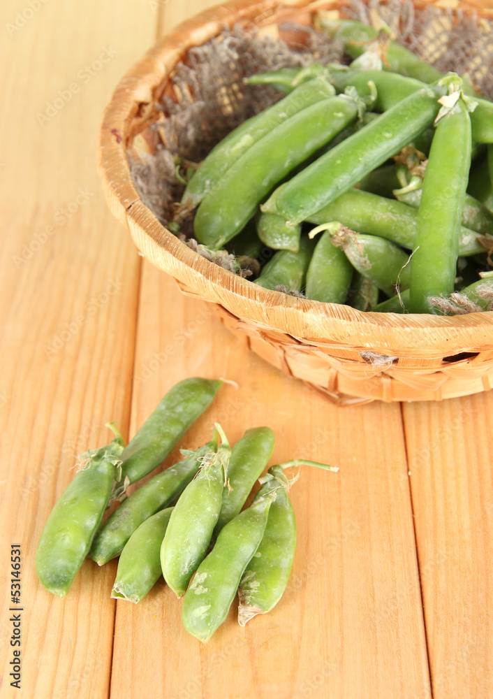 Green peas in basket on wooden table Green peas in basket on wooden table