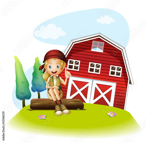 A girl sitting in front of a red barnhouse