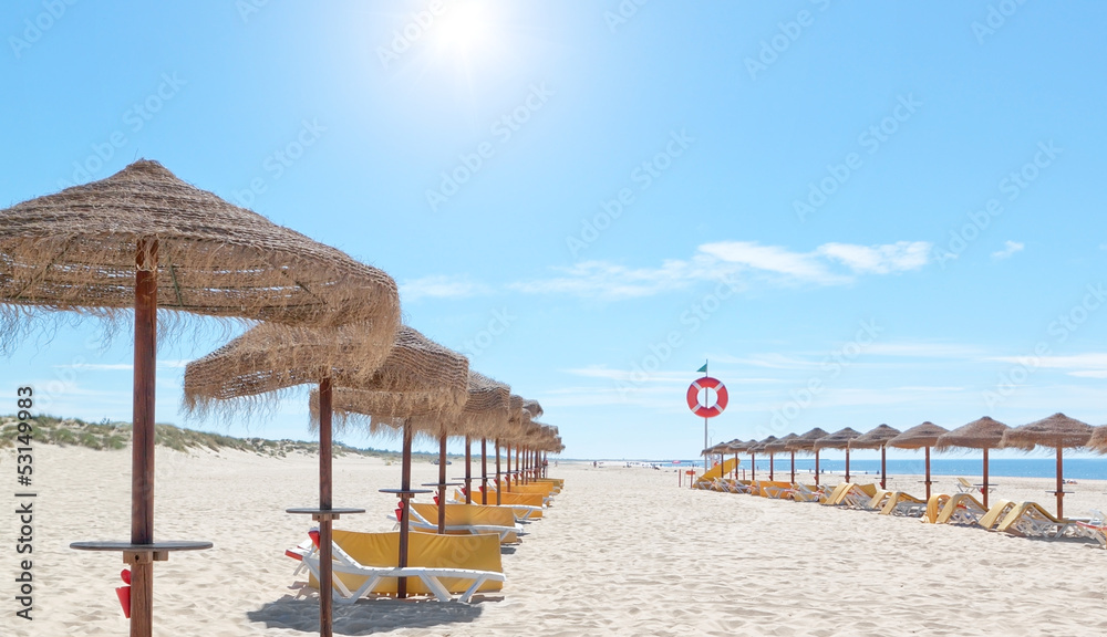 Beautiful sunny beach in Portugal with beach umbrellas and sun b