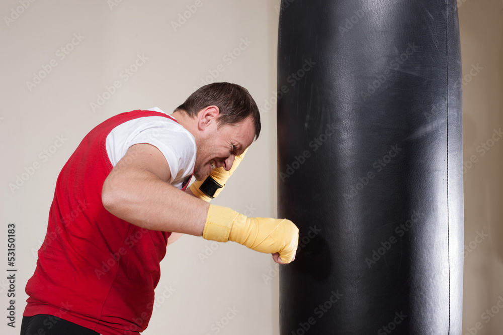 Man in boxing gloves punching bag in gym