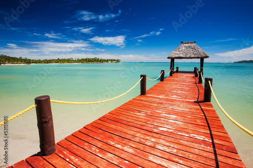 Bilde på lerret Wooden red jetty extending to tropical lagoon