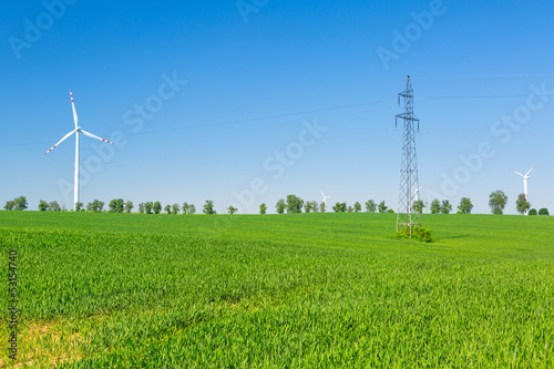 Wind turbine over blue sky on the summer field