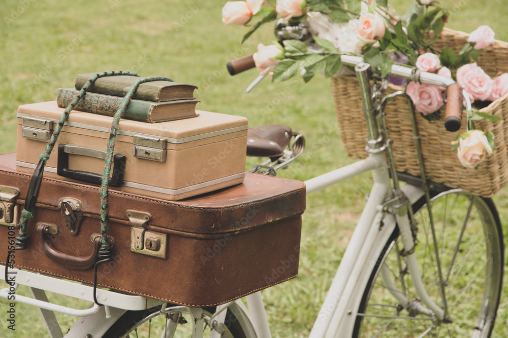 Obraz premium Vintage bicycle on the field with a basket of flowers and bag