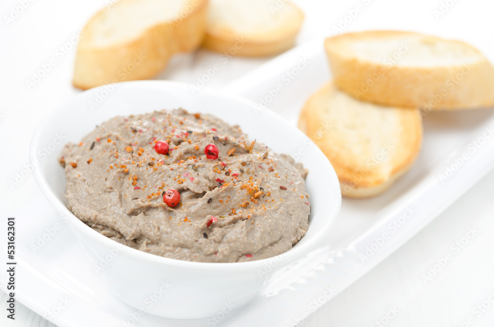 liver pate with pink pepper in a white bowl and toasted bread
