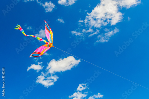 Rainbow kite flies in the blue sky