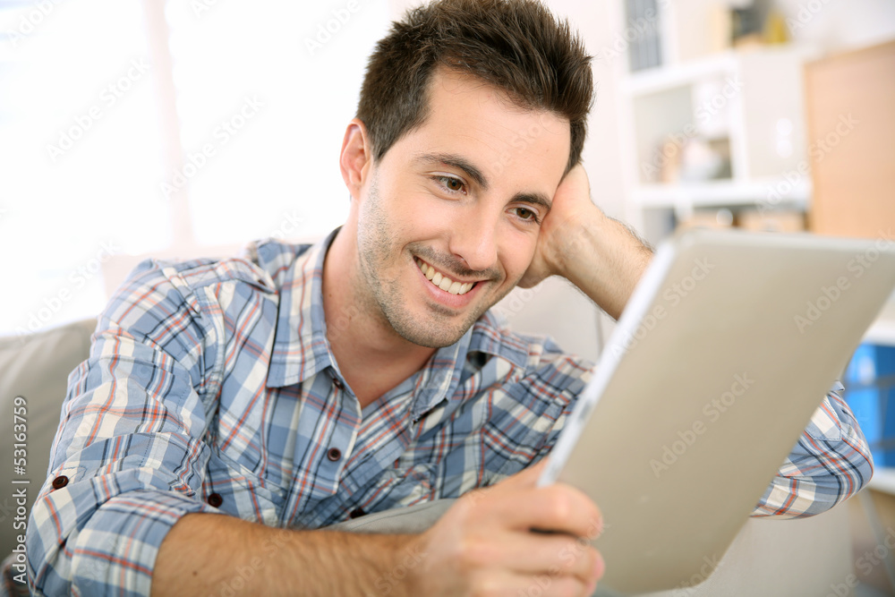 Cheerful handsome guy using tablet to read mail Cheerful handsome guy using tablet to read mail