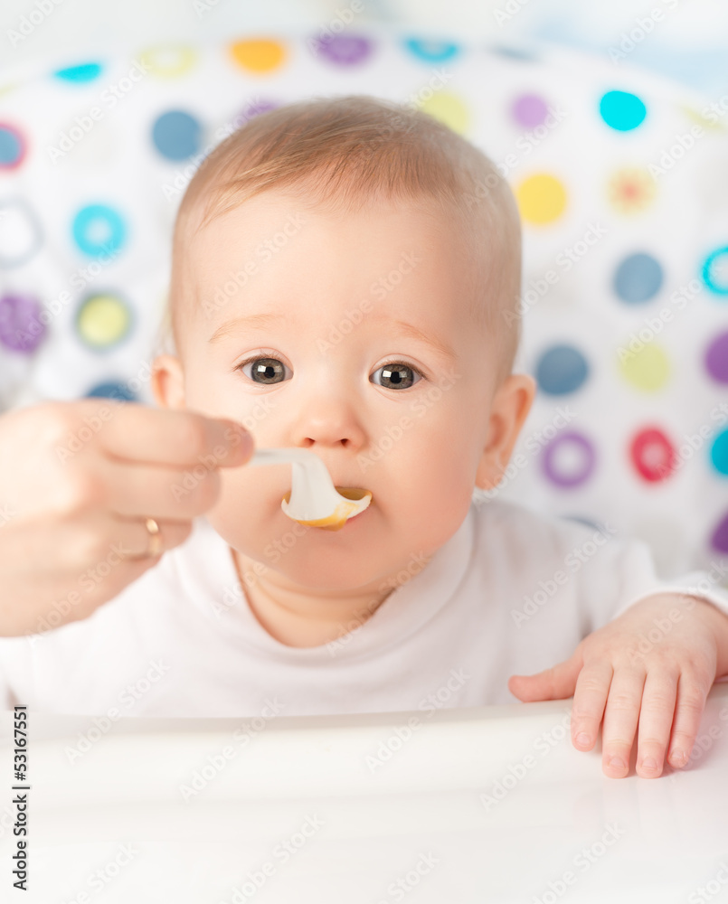 Mother feeds funny baby from spoon Mother feeds funny baby from spoon