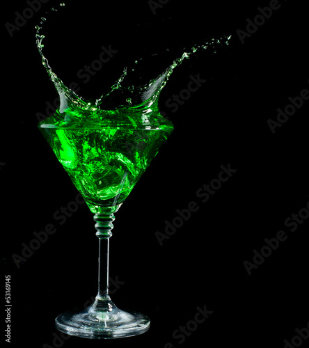 blue cocktail splashing into glass on black