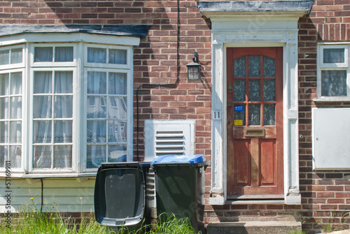 A neglected English house with rubbish bins and unkempt lawn, UK