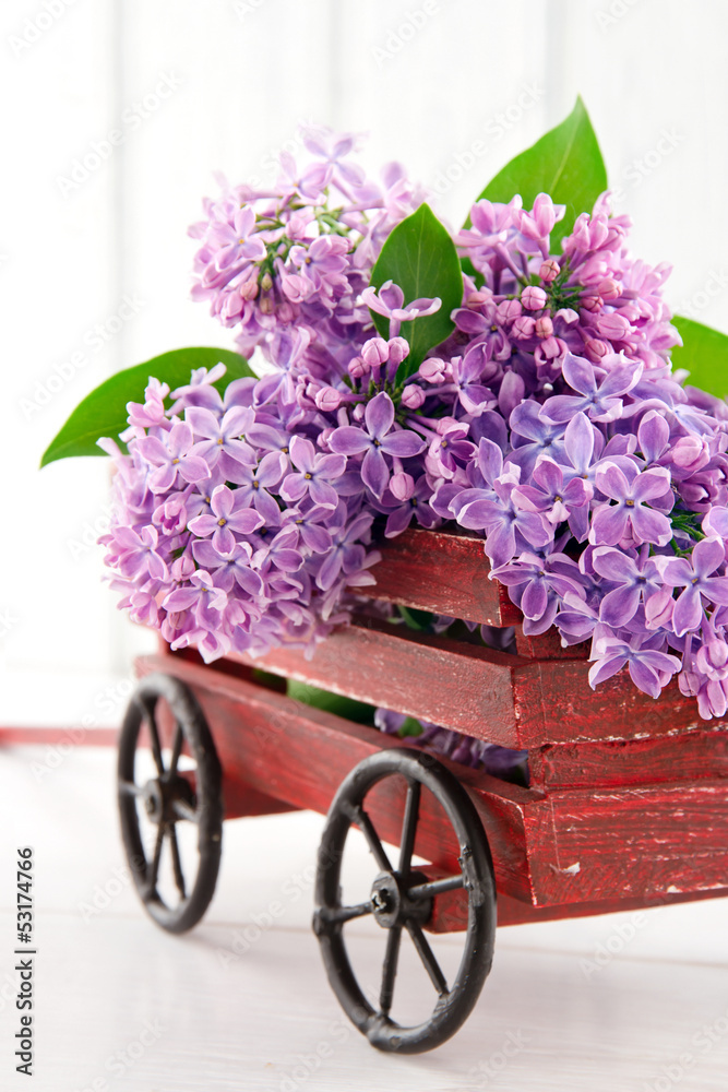Purple lilac flower bouquet in a wooden carriage
