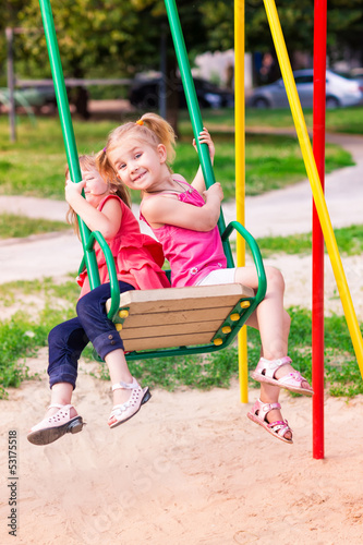 Beautiful little girl on a swings outdoor in the playground