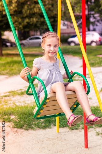 Beautiful little girl on a swings outdoor in the playground