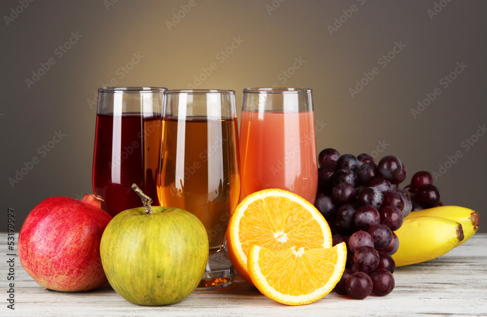 Glasses of fresh juice on table on gray background Glasses of fresh juice on table on gray background