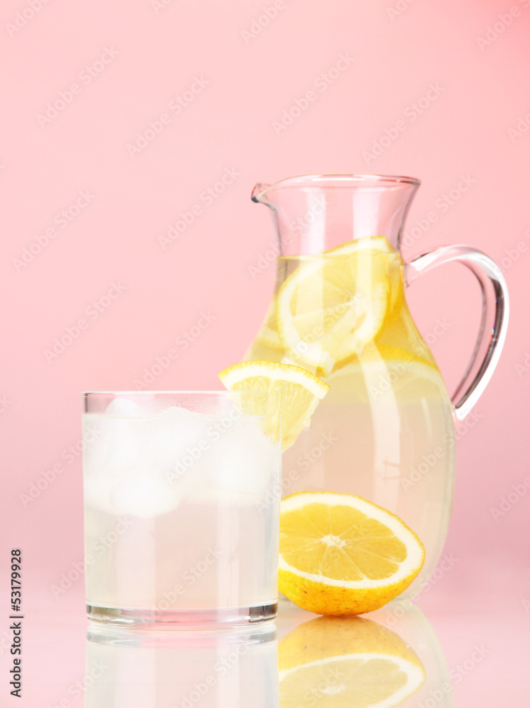 Lemonade in pitcher and glass on red background Lemonade in pitcher and glass on red background