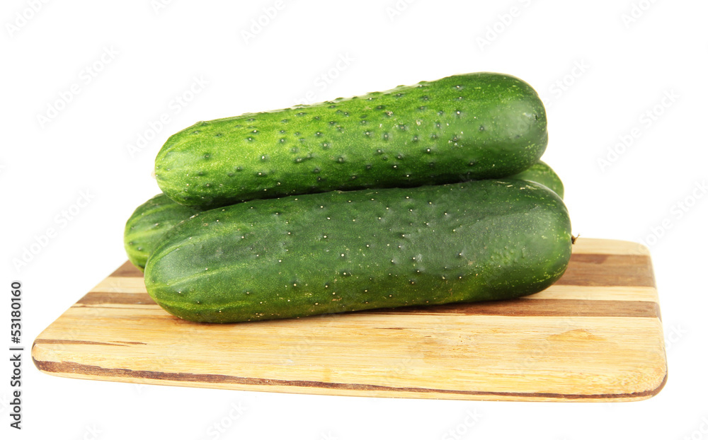 Tasty green cucumbers on wooden cutting board, isolated on