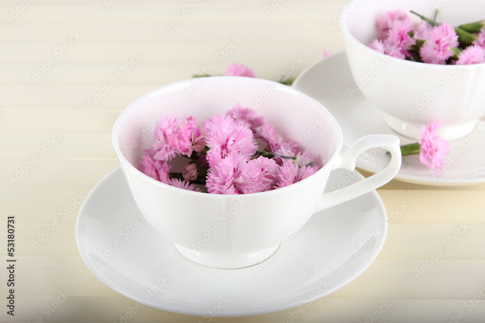 Many small pink cloves in cups on wooden background Many small pink cloves in cups on wooden background