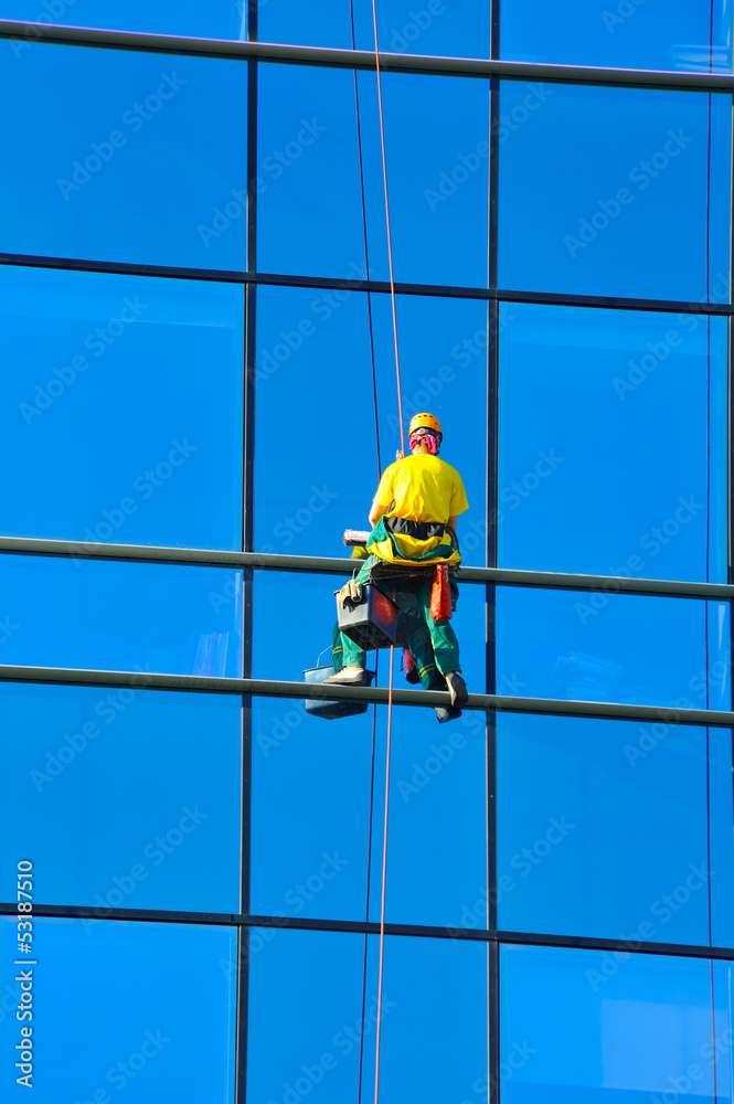 Washer wash the windows of modern skyscraper Washer wash the windows of modern skyscraper