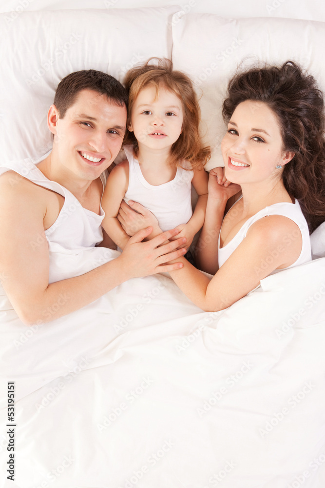 Happy family, mother, father and daughter resting on the white b Happy family, mother, father and daughter resting on the white b