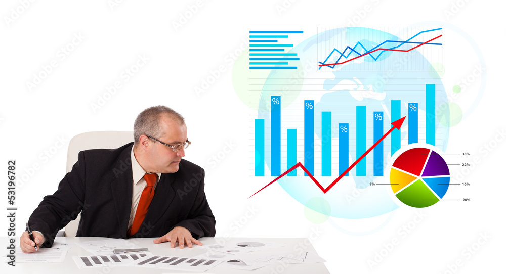 Businessman sitting at desk with statistics Businessman sitting at desk with statistics