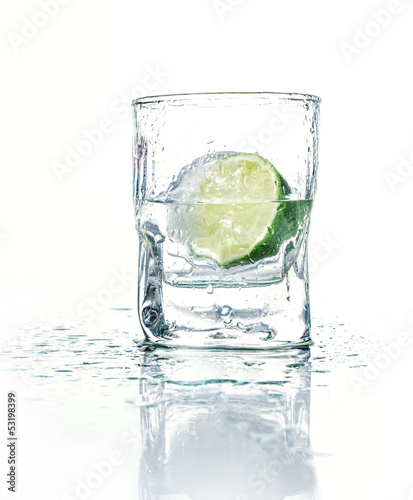 Vodka with lime in glass beaker, isolated on white